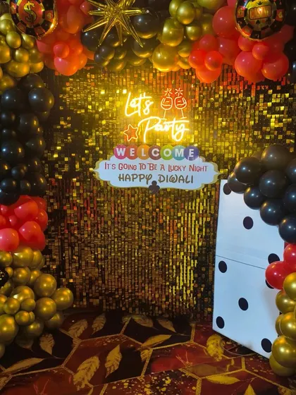 A clear shot of the Diwali card party photo booth with its gold sequin wall and balloon frame.