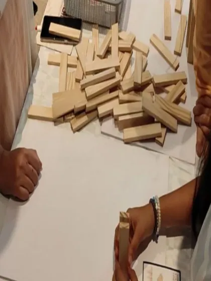 A close-up of the building blocks and hands at work. This is the core of our service: simple, eco-friendly wooden planks that become the tools for complex team-building exercises and creative expression.