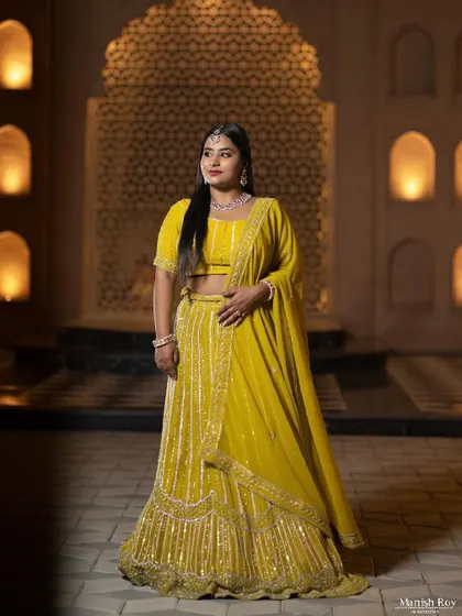 A full-length shot showing the beautiful yellow lehenga against a stunning backdrop. The makeup is bright and radiant for this evening look.