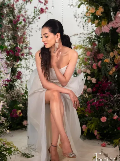 A full-length view of this modern, high-fashion look, set against a beautiful floral arch. The makeup is timeless and elegant.