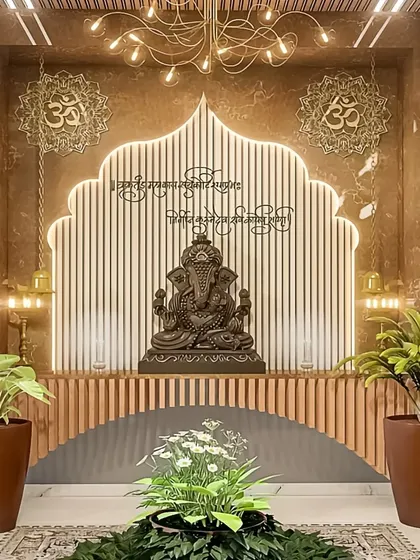 A grand and divine pooja space with a large Ganesha idol as the centerpiece. The arched backdrop with fluted panels and warm backlighting creates a serene and temple-like ambiance.
