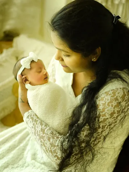 The look of love in a mother's eyes. Dressed in white lace, this mumma holds her sleeping baby, creating a soft and serene portrait of their new bond.