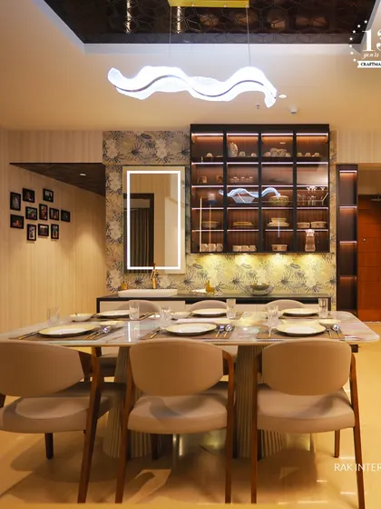 This dining room is a masterpiece of modern luxury. The design includes a stylish wash basin area with a backlit mirror, and a glass crockery unit that beautifully displays fine dinnerware.