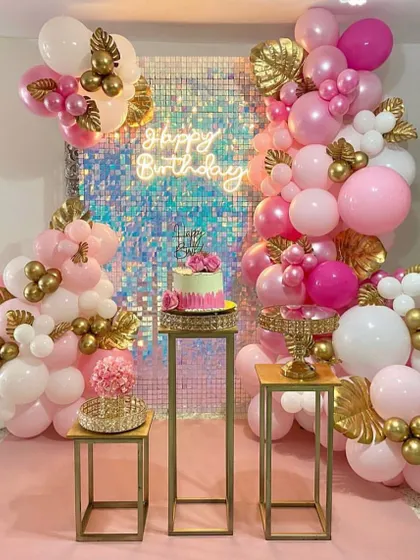 An elegant pink and gold themed party, perfect for an intimate home celebration. The decor features a shimmer wall, a neon sign, and a beautiful balloon arrangement with gold leaf details.