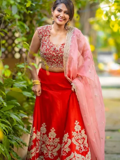 A vibrant and happy look. The bright red lehenga is paired with soft, natural makeup and a simple updo, letting her joyful smile be the focus.