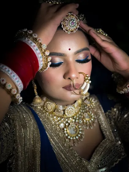 A dramatic close-up of the Rajputi bride with her eyes closed. The dark background makes the blue winged eyeliner and her gold jewelry stand out beautifully.