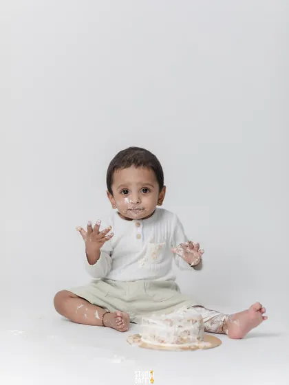 The aftermath of the cake smash, with frosting everywhere and a happy baby.