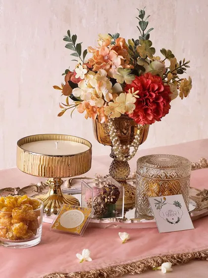 For a truly bright and blissful gift, our Bright Bliss hamper includes a large candle, truffles, a glass jar with butter cookies, and a flower arrangement on a mirror tray.