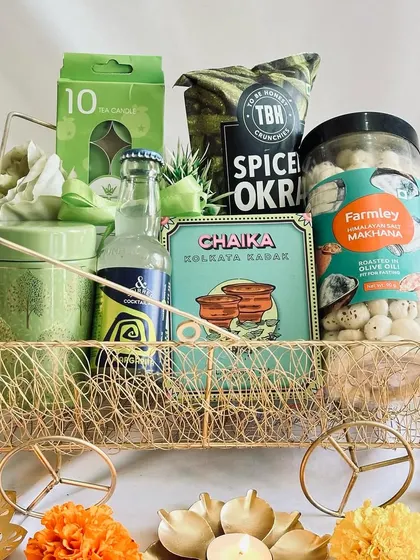 This hamper is perfect for a tea lover, featuring "Chaika" tea, snacks, and scented candles in a cohesive green color scheme.