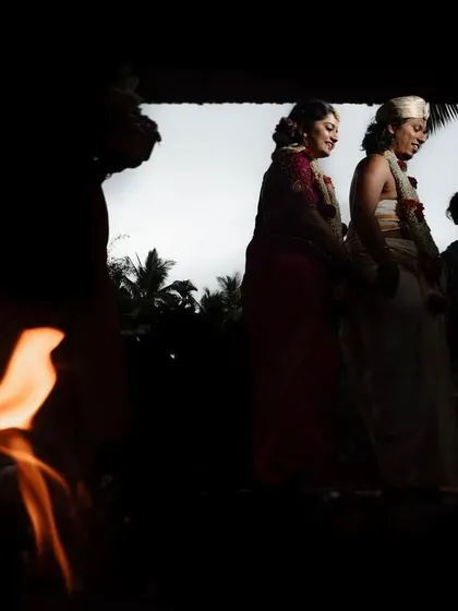 A creative shot of the sacred fire (agni) during a Hindu wedding ceremony, with the couple silhouetted in the background. This artistic angle highlights a central element of the ritual.