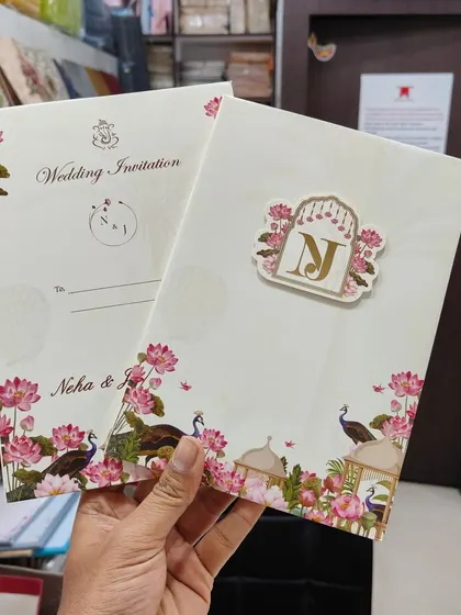 Here is a closer look at a Pichwai-themed invitation with a personalized gold tag. The design features beautiful lotuses and peacocks, blending sacred art with bespoke details for your wedding.