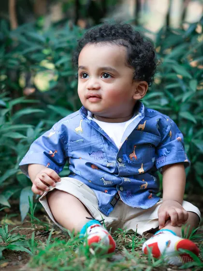 A curious toddler sits among the green foliage, his bright eyes taking in the world around him. Outdoor sessions allow kids to explore and be their natural selves.