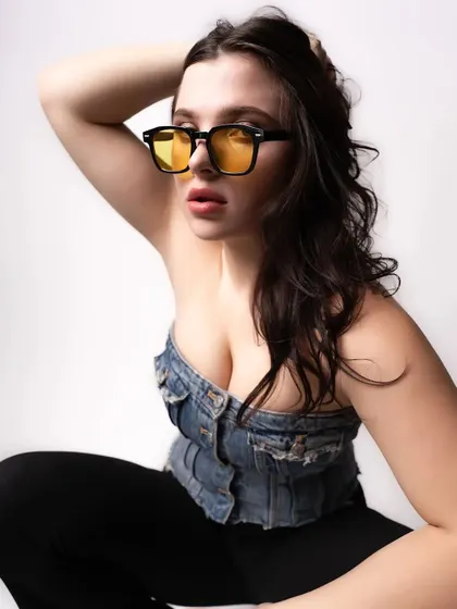 A close-up from the same denim-themed shoot, focusing on the model's expression and the stylish yellow-tinted glasses. This type of shot is great for accessory and beauty features.