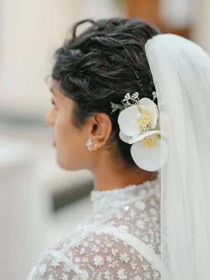 A close-up of the bride's elegant hairstyle, adorned with a white orchid. This shot highlights the delicate and thoughtful details of her bridal look.