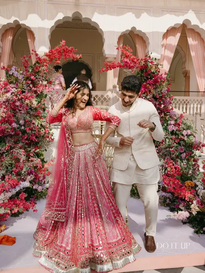 A candid, joyful moment of the couple dancing, framed by bougainvillea installations. The decor is designed to create beautiful backdrops for these spontaneous, happy memories.
