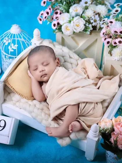 A full view of the miniature bed setup against a bright blue background. The calendar block adds a personal touch to commemorate the baby's birth date.