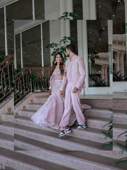 The couple descends a staircase, showcasing their stylish, coordinated pink outfits for the Haldi carnival.