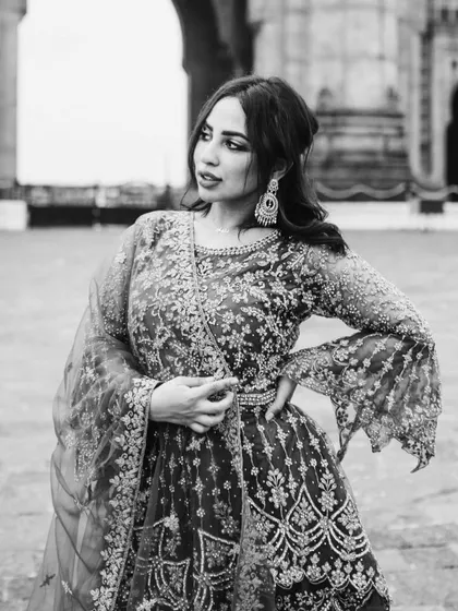 The same elegant pose captured in black and white. This version highlights the incredible texture and detail of her embroidered dress.