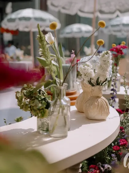 An artful close-up of the floral details, with delicate white and yellow blooms in small glass vases. The soft focus and natural light highlight the fresh, organic beauty that defined this spring luncheon.