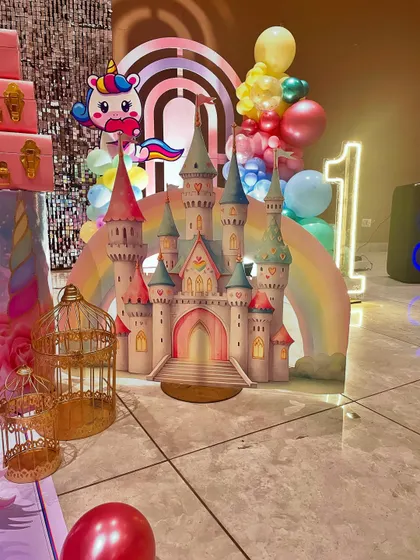 Another angle of the unicorn party setup, highlighting the castle cutout, a large light-up number '1', and decorative birdcages that add to the whimsical feel.
