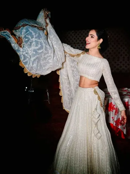 The same beautiful white Chikankari lehenga, captured in a moment of joy. The lightweight dupatta with a scalloped gold border adds to the grace and movement of the outfit.