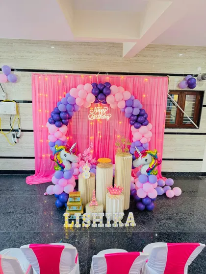 A wider shot of the unicorn theme party, showing the setup in the context of the room with guest chairs in the foreground. I can adapt my decorations to fit any party space.