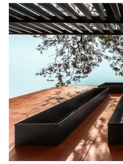 An upward view of the facade's fenestrations. The deep, box-like window frames are designed to control sunlight and create a powerful geometric pattern against the red textured surface.