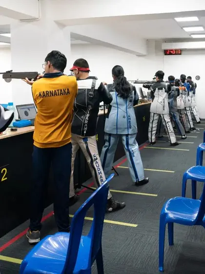 A view from behind the athletes during the CISCE National Games. The range is set up for a major competition, with electronic targets and designated lanes.