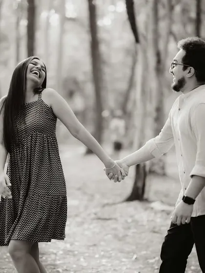 A black and white shot of the couple walking hand-in-hand through the forest, laughing together. It’s a classic example of a candid moment that feels both timeless and full of life.