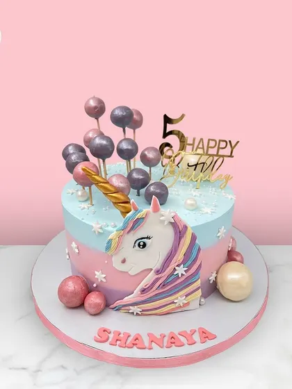 A magical unicorn cake for Shanaya's 5th birthday, featuring a pastel rainbow mane and a cascade of candy-like spheres.