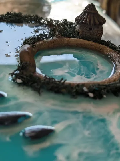 A detailed shot of the tiny, handcrafted hut and mossy island surrounded by swirling resin water.