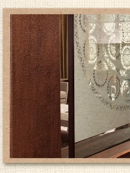 A detail from the Modi Residence, showing a hammered copper panel next to a glass screen with a Sanjhi-inspired design. This juxtaposition of textures, from rough metal to delicate etching, is a hallmark of our material-driven approach.