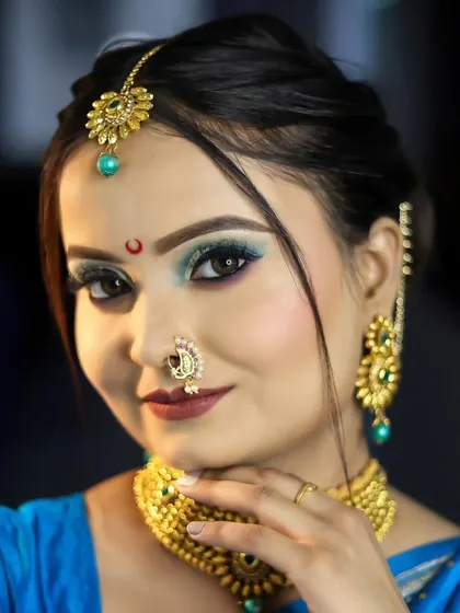A confident pose showcasing the student's skill in creating a flawless base and striking eye makeup that complements the traditional attire.