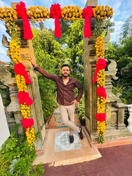 Posing against a floral arch at a wedding event. I'm here to celebrate with you and make your special day sound amazing.
