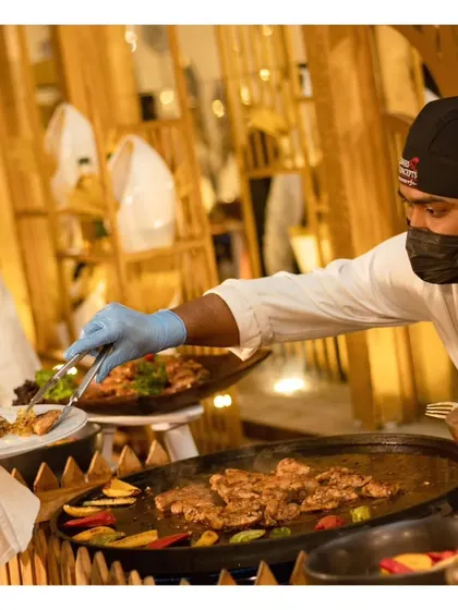 Another shot of our chef serving a guest from the live grill, emphasizing the fresh, made-to-order nature of our food.
