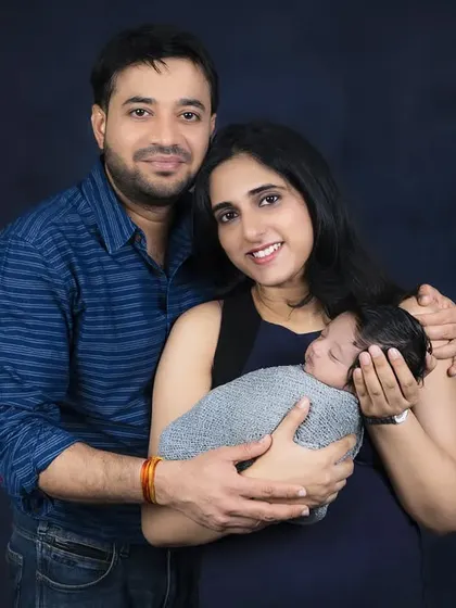 A beautiful portrait of new parents holding their sleeping baby. Their loving embrace and happy smiles tell a story of a new family beginning.