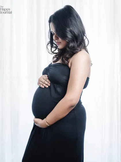 This classic pose against a softly lit curtain is timeless. The focus is entirely on the mother-to-be and the special bond she already shares with her baby.
