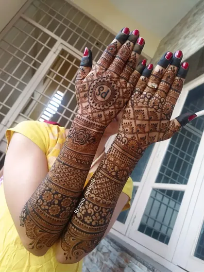 A beautiful full-arm bridal design that incorporates the couple's initials "SD" in a central mandala. The rest of the design is a rich tapestry of geometric jaali work and floral bands.