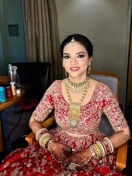 The complete look for this bride in her Dolly J lehenga. The makeup is balanced, with a focus on the eyes and a neutral lip to complement the heavy outfit.
