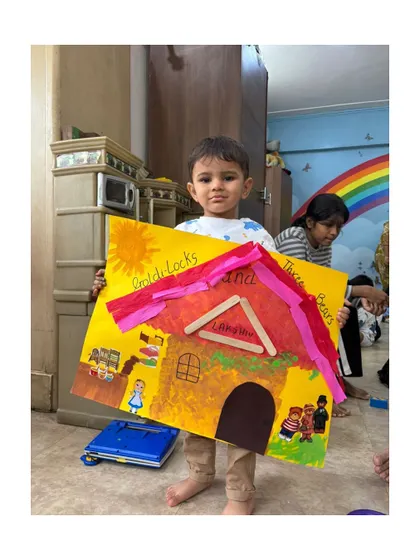 This young artist proudly displays the bear's cottage he created, complete with a popsicle stick roof.