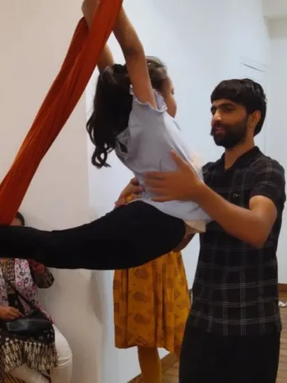 I believe in making yoga fun for kids. Here, I'm assisting a young student in an aerial pose, helping her feel safe and confident.