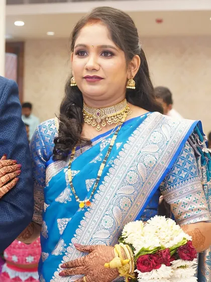 A close-up of the bride's reception look. The makeup features a defined eye and a classic lip color that complements her beautiful blue saree.