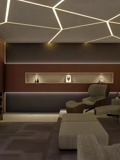 A modern home theater with geometric LED lighting on the ceiling. The room features a mix of lounge chairs and sofas, providing a comfortable and stylish space for watching movies.