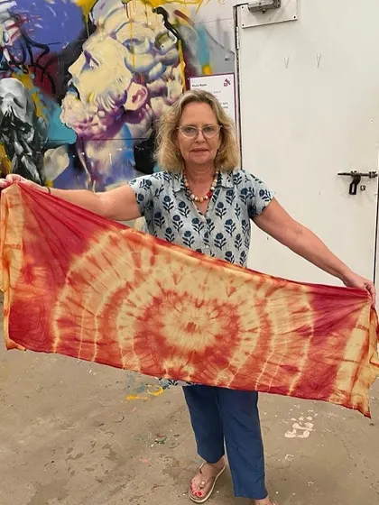 A participant proudly displays her finished organic cotton stole, dyed with natural colors. The circular patterns she created are absolutely stunning.