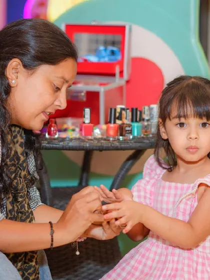 A little girl gets a fun and colorful manicure from one of our staff members during a spa party.