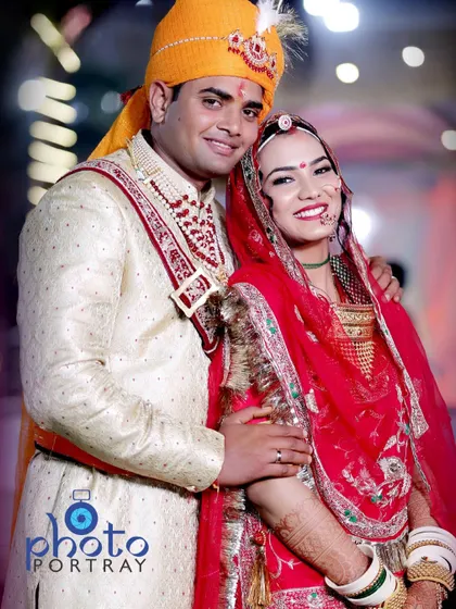A classic posed portrait of the smiling couple in their traditional Rajasthani wedding attire.