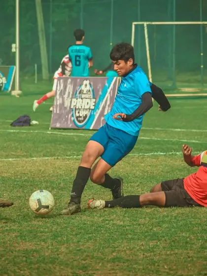 A player skillfully dribbles past a sliding opponent.