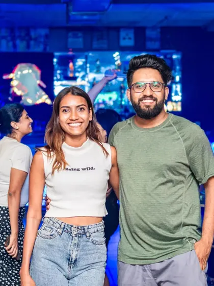 A couple enjoying the party atmosphere. The background shows the dance floor is busy and the night is young.