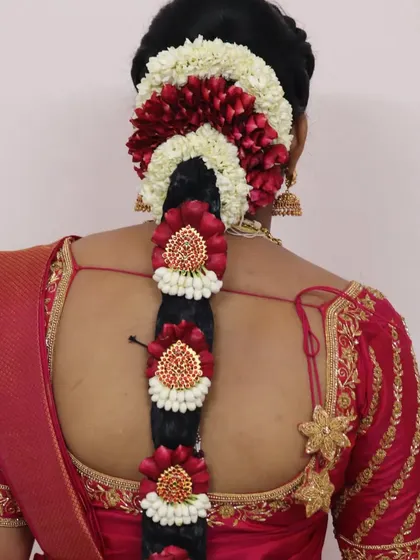 A traditional South Indian bridal braid with a modern twist. The braid is decorated with fresh red and white flowers in a beautiful pattern, creating a unique and eye-catching hairstyle.