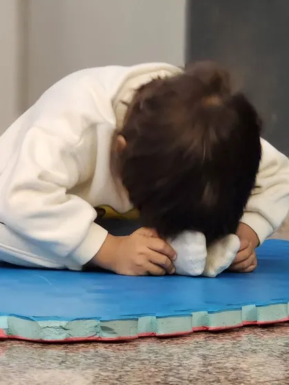 This toddler is fully engaged in a butterfly stretch. These simple, gentle exercises are perfect for improving hip flexibility and are a core part of our creative movement curriculum for young children.